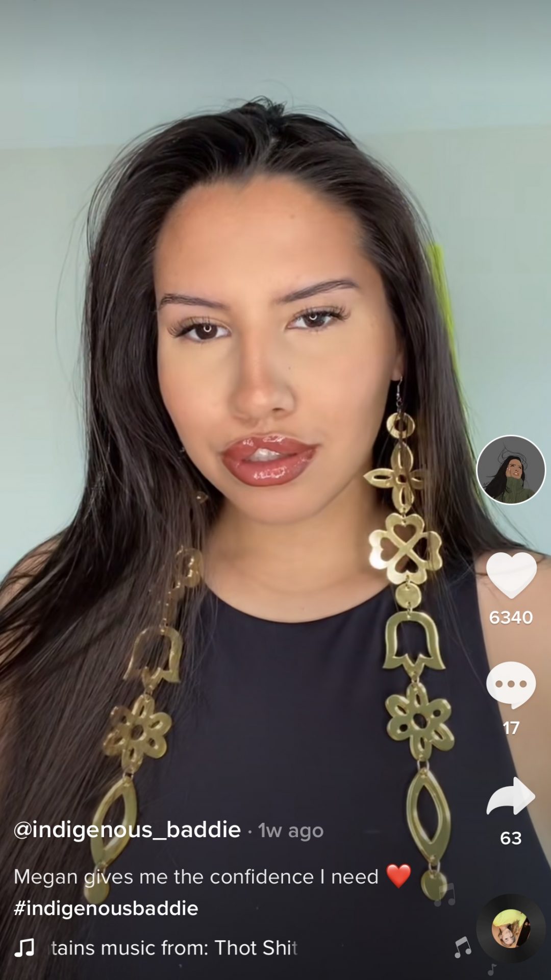 Screenshot image of an Indigenous female TikTok influencer with long brown hair and large gold Indigenous earrings looking at the camera
